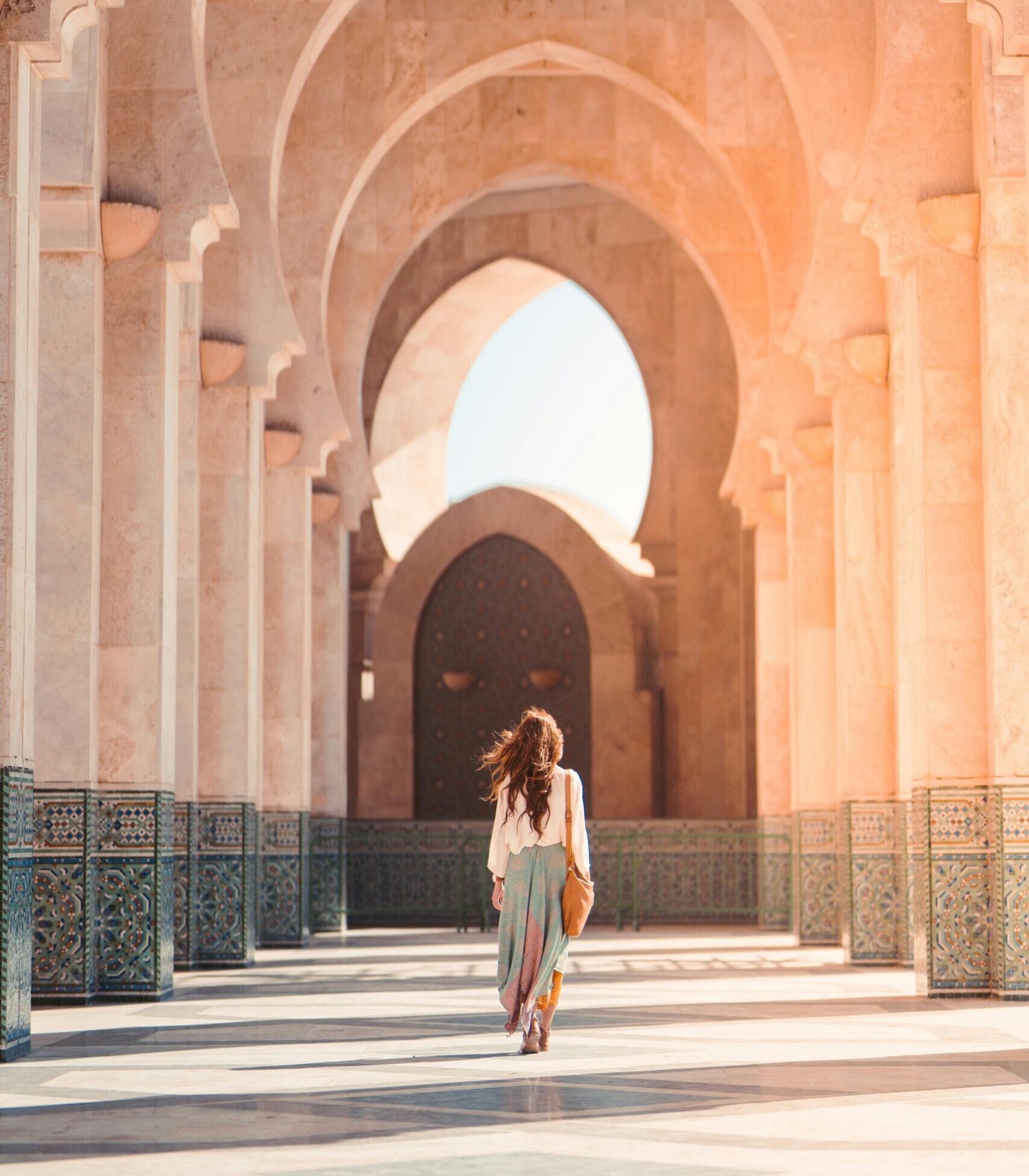Femme marchant sous des arcades marocaines ensoleillées