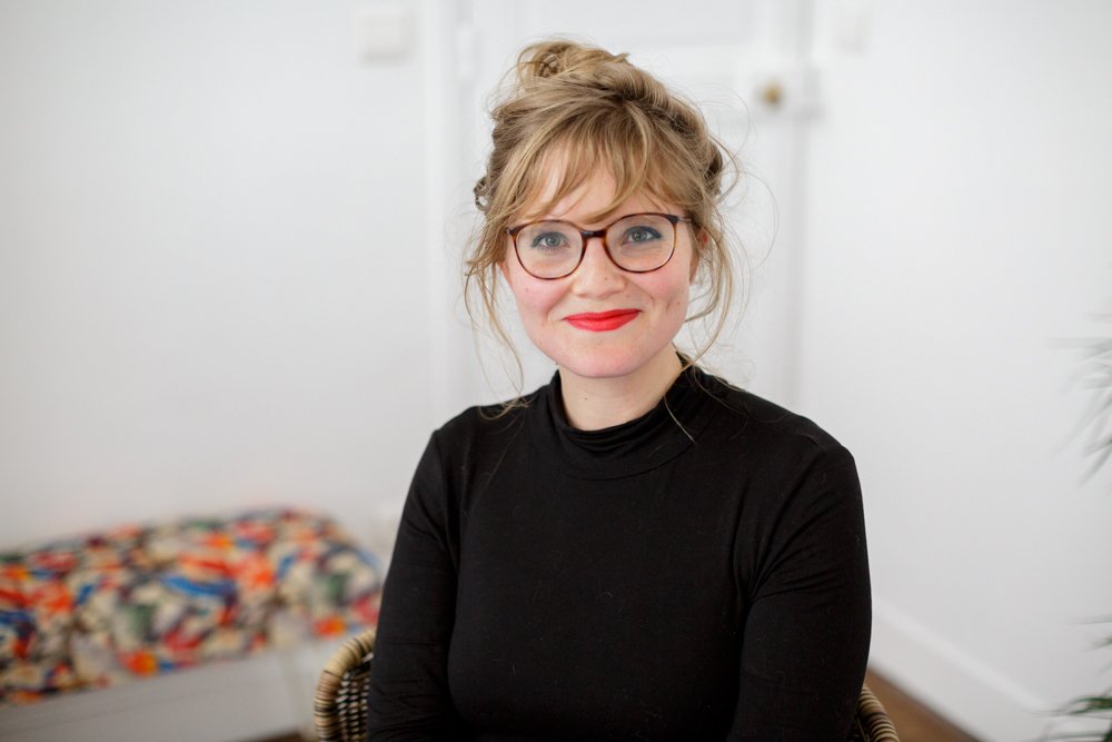 Personne souriante portant des lunettes assise à l’intérieur