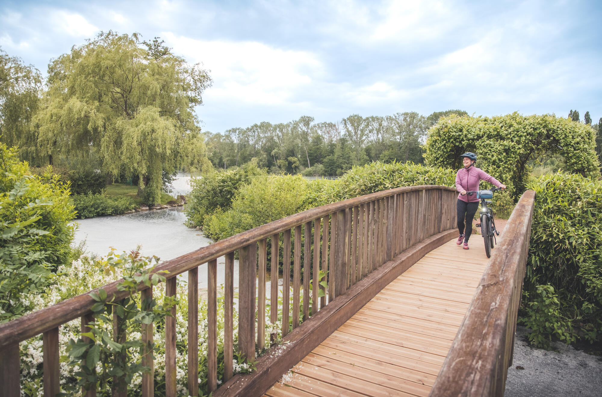 Cycliste sur un pont en bois verdoyant