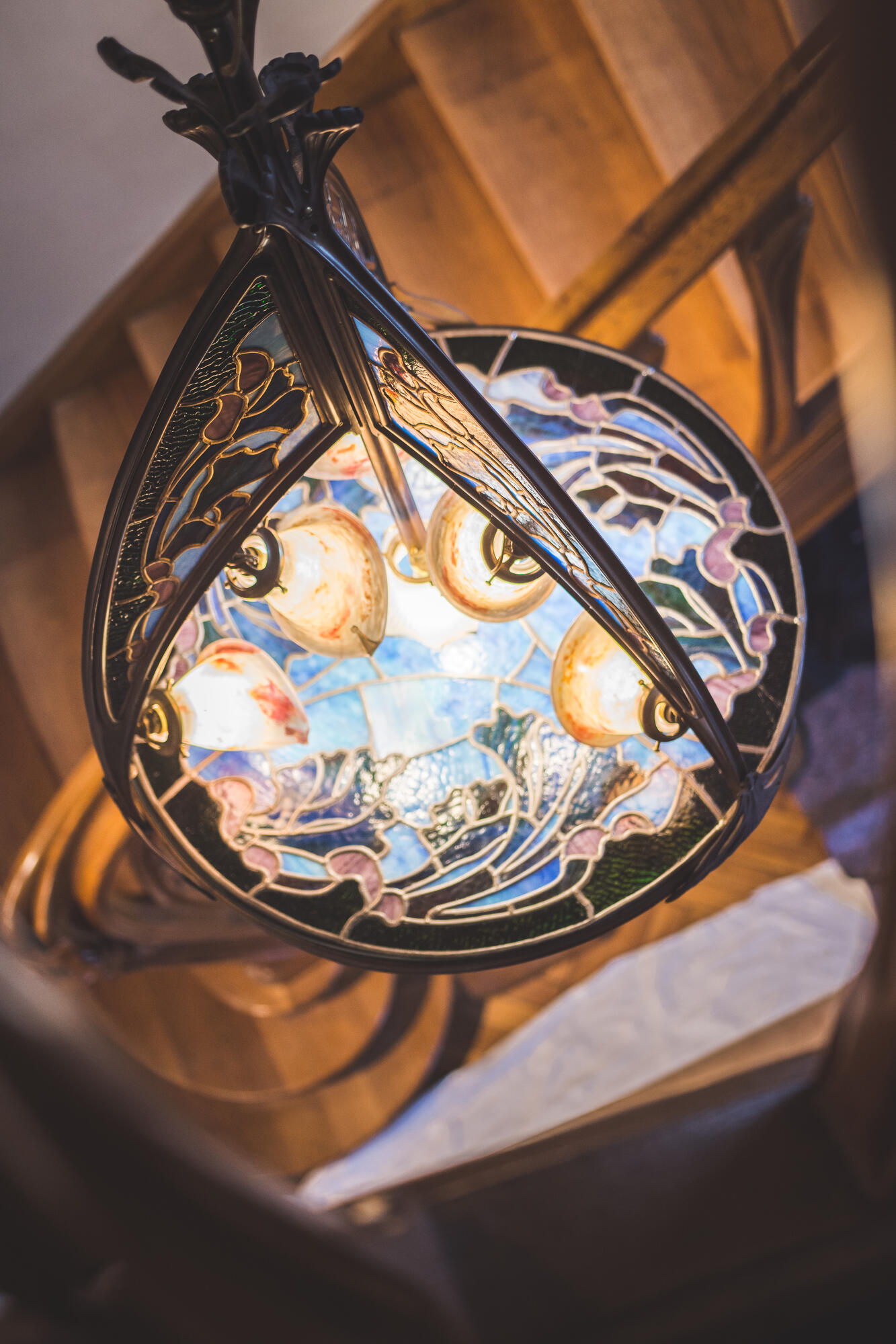 Luminaire art nouveau au-dessus d’un escalier en bois