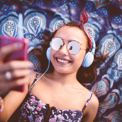 Jeune femme souriante écoutant de la musique et prenant selfie