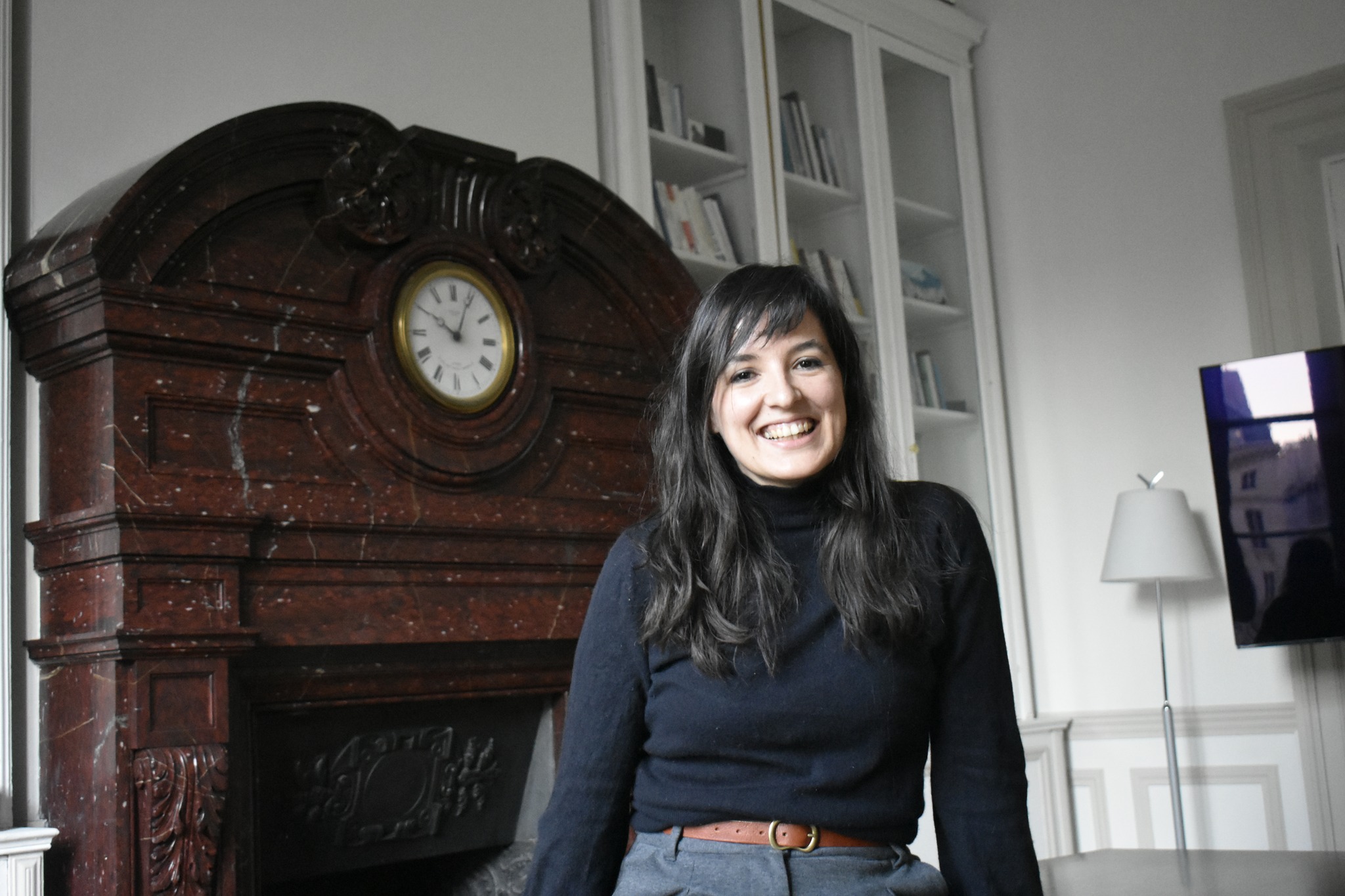 Femme souriante devant une cheminée ancienne