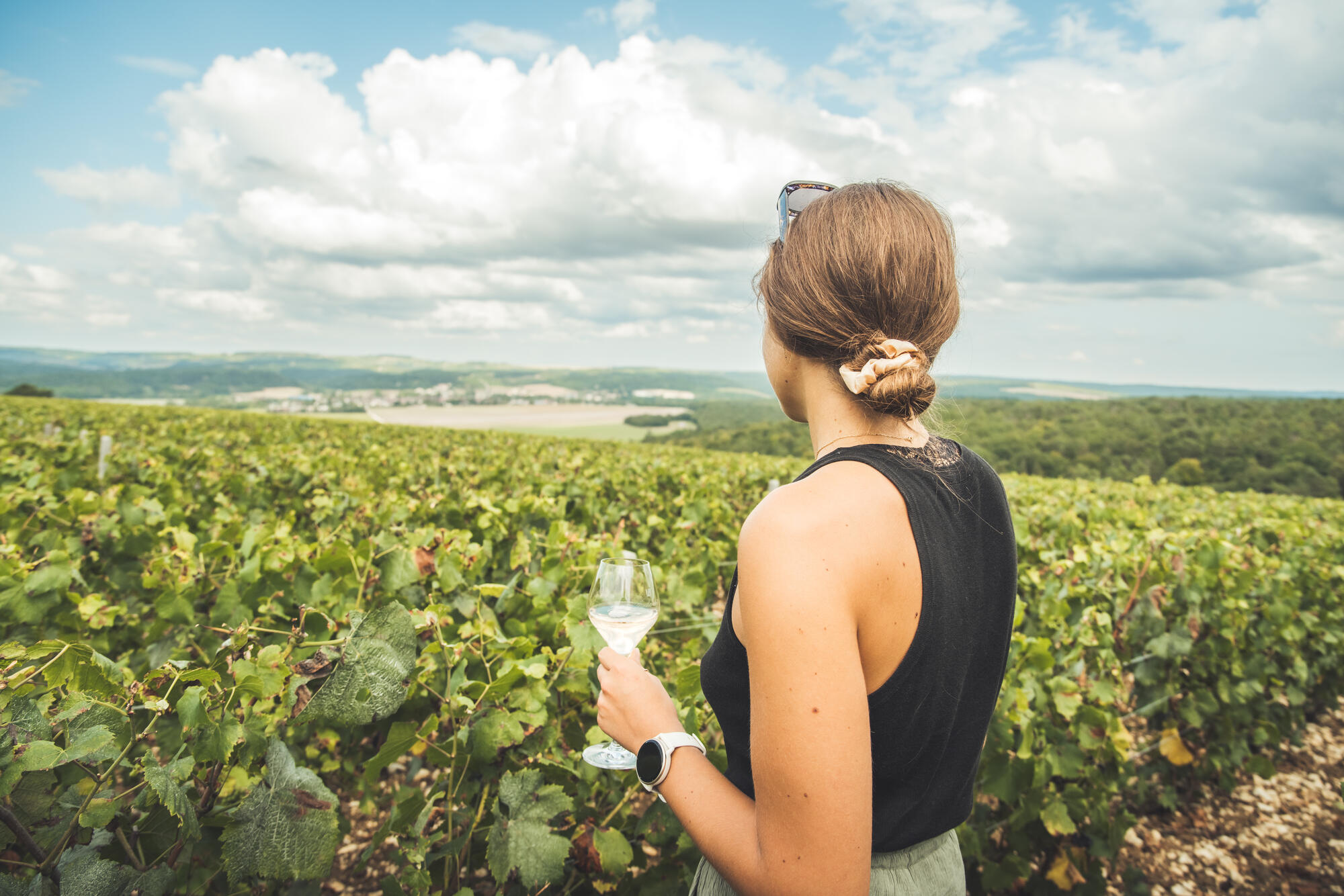 Femme observant un vignoble avec un verre de vin