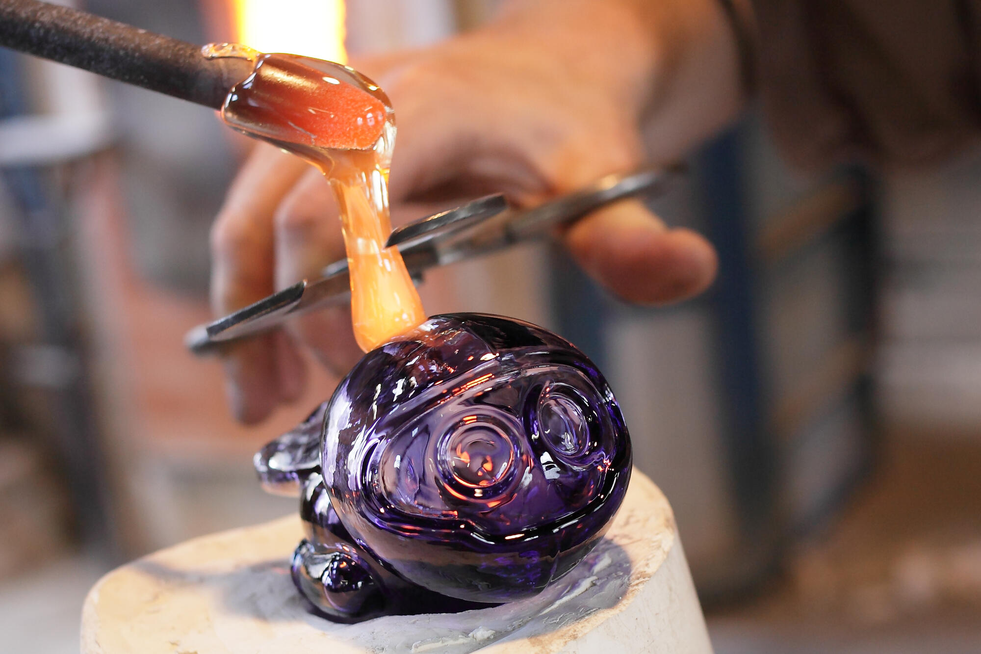 Souffleur de verre façonnant sculpture en verre violet