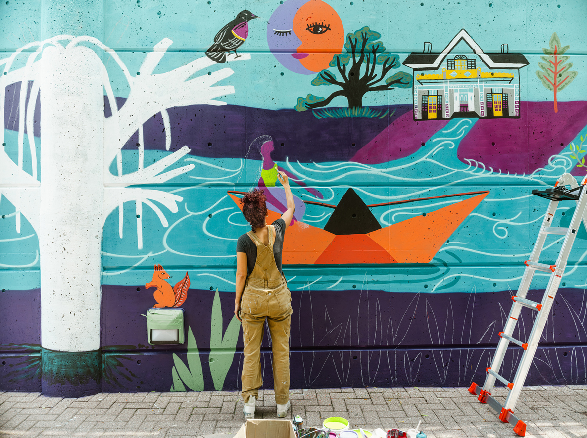 Artiste peignant une fresque colorée sur un mur.