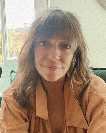 Femme souriante assise près d'une fenêtre lumineuse