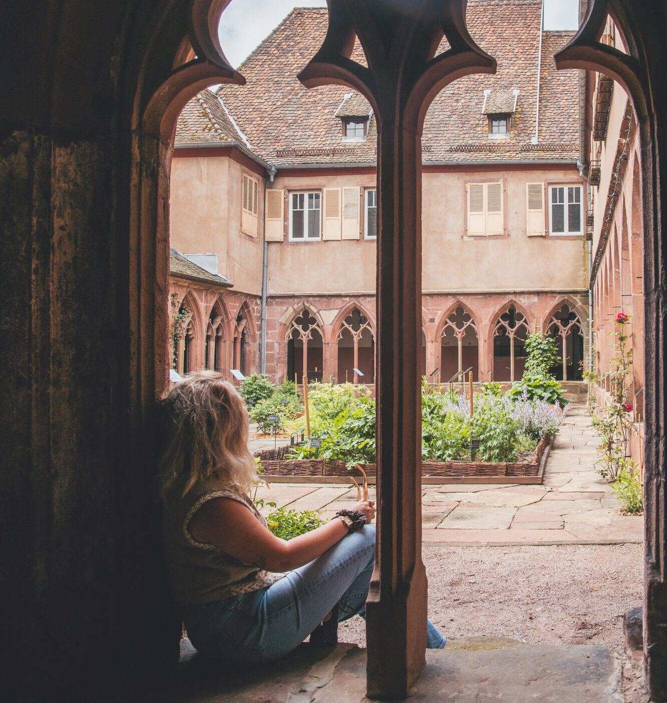 Personne assise dans un cloître médiéval fleuri