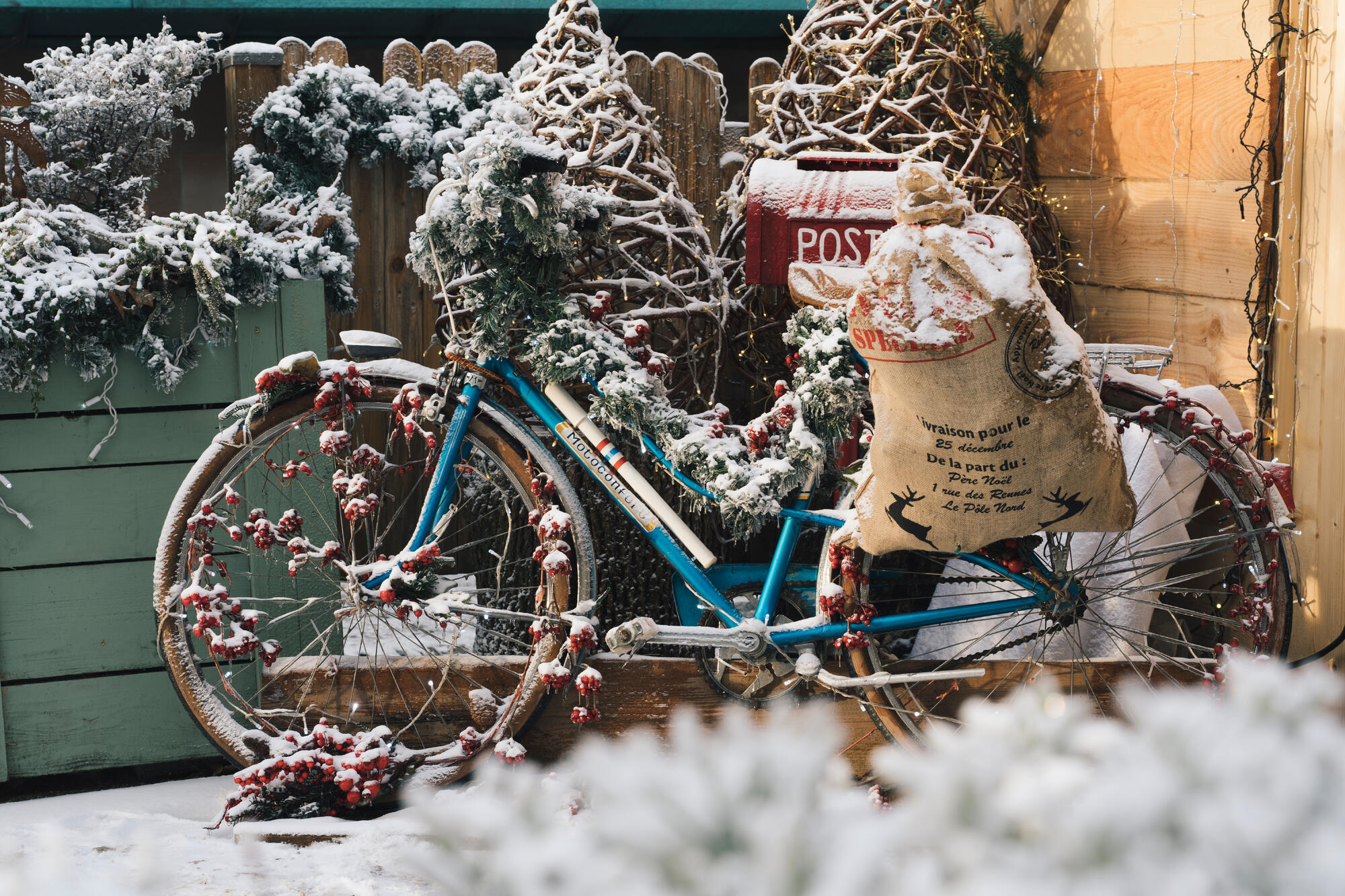 Vélo bleu décoré de Noël sous la neige.